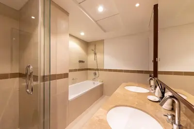 a bathroom with two sinks and a shower and a tub at Elegant 2BR Balcony and Stunning Burj Views in Dubai