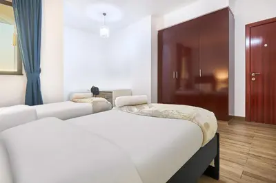 a bedroom with a white bed and a brown door at 3-Bedroom Residence in Murjan 5 - Jumeirah Beach with Sea Views in Dubai