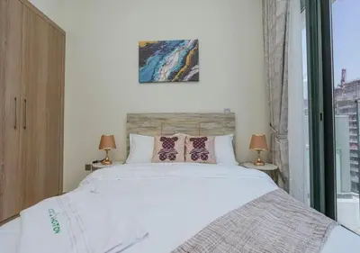 a bedroom with a large white bed with two lamps at Stylish Meydan Studio with Private Balcony in Dubai