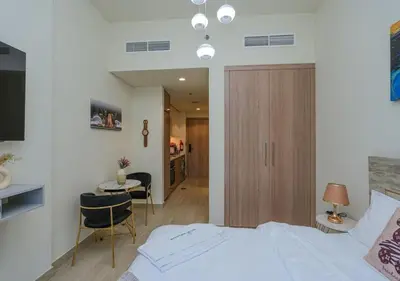 a bedroom with a bed and a table and a kitchen at Stylish Meydan Studio with Private Balcony in Dubai