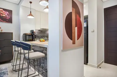 a kitchen with a counter with blue bar stools at Nobles Tower Business Bay - Modern 1-Bedroom Apartment in Dubai