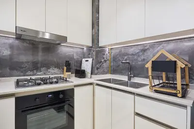a kitchen with white cabinets and a stove top oven at Nobles Tower Business Bay - Modern 1-Bedroom Apartment in Dubai