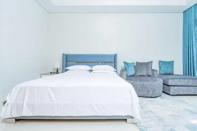 a white bedroom with a bed and a couch at Nasma Luxury stays- Lavish with luxury facilities in Aykon city in Dubai