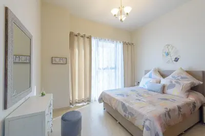 a bedroom with a bed and a large window at Cozy and modern 1 BR Apt in Al Furjan in Dubai