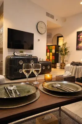 a table with two plates and wine glasses on it at Artistic Studio in Cayan Tower with Marina Views in Dubai