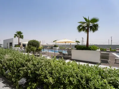 a resort with a pool and palm trees and chairs at Homely Bliss Studio in Azizi Riviera-12 in Dubai
