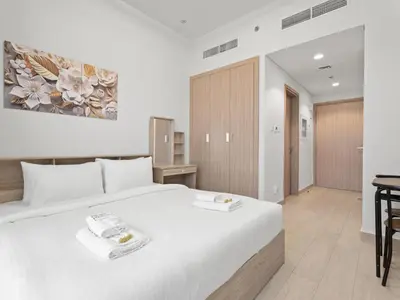 a bedroom with a large white bed and a desk at Homely Bliss Studio in Azizi Riviera-12 in Dubai