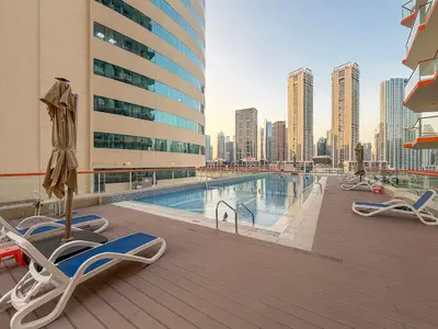 a balcony with chairs and a swimming pool on a building at FIRST CLASS Studio Canal & Burj Khalifa View in Dubai
