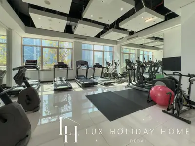 a gym with a lot of treadmills and ellipticals at LUX The 02 Residences JLT Suite in Dubai