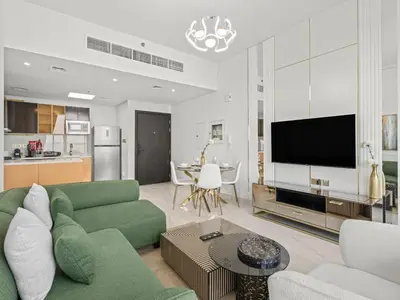 a living room with a green couch and a kitchen at Exclusive Gemz Stay 2BR plus Study w Private Pool-07 in Dubai