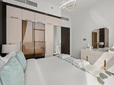 a bedroom with a white bed with blue pillows at Exclusive Gemz Stay 2BR plus Study w Private Pool-07 in Dubai