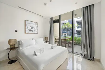 a white bedroom with a large bed and a balcony at FIRST CLASS 2BR Modern Luxury Hideaway in Dubai