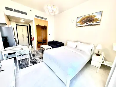 a white bedroom with a bed and a desk at 25 Studio Skyz By Danube, Arjan in Dubai