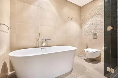 a white bath tub in a bathroom with a toilet at Jumeirah Living Marina Gate - Elegant 1BR Canal View Retreat in Dubai