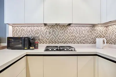 a kitchen with white cabinets and a microwave at Jumeirah Living Marina Gate - Elegant 1BR Canal View Retreat in Dubai