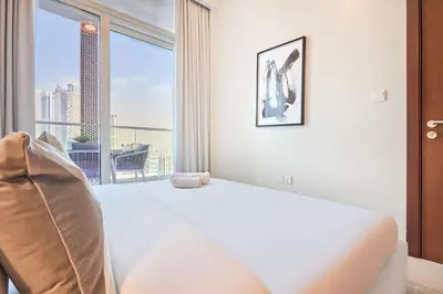 a bedroom with a white bed and a large window at Reva Residences 1BR - Near Downtown Dubai & Canal Walk in Dubai