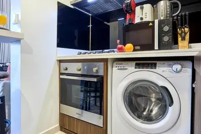 a kitchen with a washing machine under a counter at Reva Residences 1BR - Near Downtown Dubai & Canal Walk in Dubai