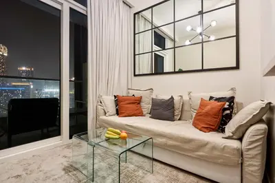 a living room with a couch and a glass table at Reva Residences 1BR - Near Downtown Dubai & Canal Walk in Dubai