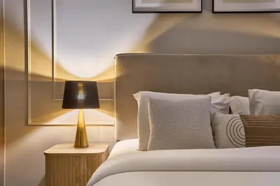 a bedroom with a bed with a lamp on a table at Stylish 1BR near Miracle Garden - Oxford Gardens in Dubai
