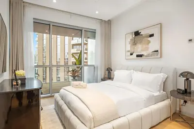 a white bedroom with a large bed and a window at FIRST CLASS 1BR Panoramic Marina Views in Dubai