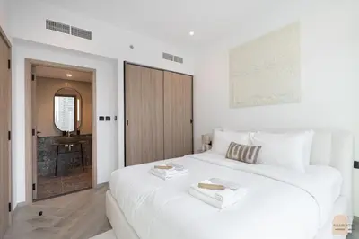 a white bedroom with a large white bed and a door at Skyview Experience View Burj Khalifa Pool, Canal in Dubai