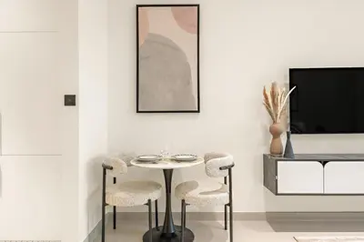 a dining room with a table and two chairs and a tv at FIRST CLASS Studio Private Jacuzzi Canal View in Dubai