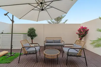 a patio with three chairs and a table and an umbrella at FIRST CLASS VILLA Zen Luxe Contemporary Haven in Dubai