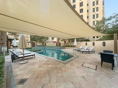 a patio with a large umbrella and a pool at FIRST CLASS 2BR Old Town Burj View Retreat in Dubai