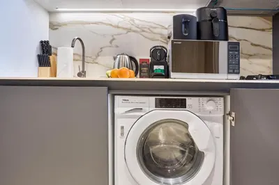 a washing machine with a microwave on a shelf at Modern Studio at Oxford Gardens Arjan - Near Miracle Garden in Dubai