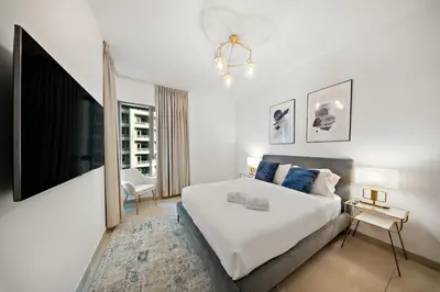 a white bedroom with a bed and a tv at FIRST CLASS 1BR Sophisticated Downtown Escape in Dubai