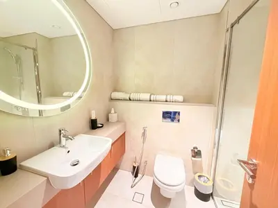 a bathroom with a sink and a toilet and a mirror at City Glow Comfort Studio - Oasis Pool in Dubai