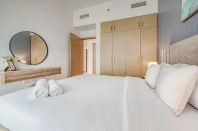 a bedroom with a large white bed with towels on it at Luxury Sea View 1BR in JBR with easy Bluewaters Access in Dubai