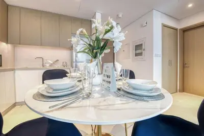 a white dining room table with a vase of white flowers at Luxury Sea View 1BR in JBR with easy Bluewaters Access in Dubai