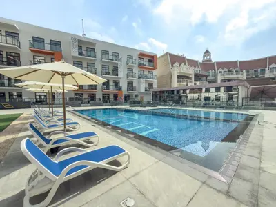 a swimming pool with lounge chairs and an umbrella at Luxury 1BR Apartment in Binghatti Mirage JVC Dubai in Dubai