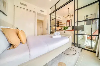 a bedroom with a white bed and a glass wall at Stunning 1 B R in Dubai Hills in Dubai