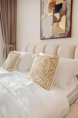 a white bed with two pillows on top of it at Cozy JVC Studio I Pool & Gym I Fully Furnished in Dubai