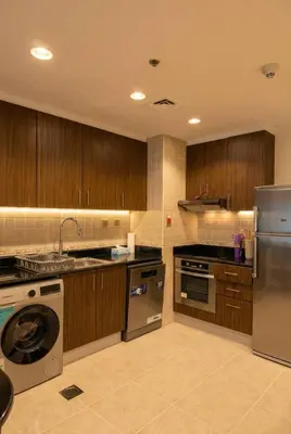 a kitchen with stainless steel appliances and wooden cabinets at High-Floor Marina 1BR Apartment | Skyline Views in Dubai