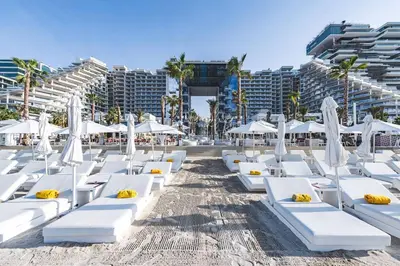 a beach with white lounge chairs and umbrellas at FIVE Palm | Stunning Sea-View Luxury 2BR Apartment in Dubai