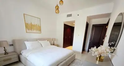 a white bedroom with a bed and a table at Yansoon 3 Downtown, Dubai in Dubai