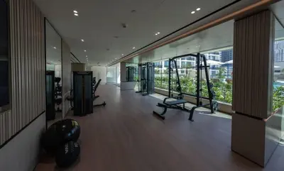 a gym with cardio equipment in a building with windows at Chic & Peaceful Studio Retreat Binghatti Aurora in Dubai