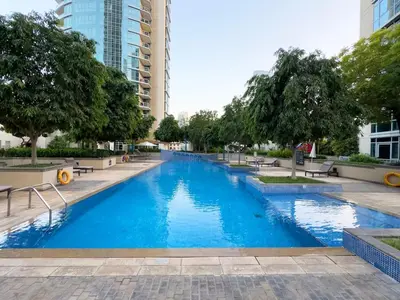 a large blue swimming pool with trees and buildings at BurjKhalifa l Live show fountain view 3BR Downtown in Dubai