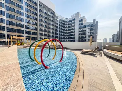 a pool with a water slide in front of a building at Frank Porter - Azizi Beach Mirage in Dubai