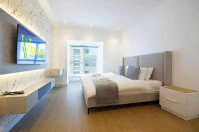 a white bedroom with a large bed and a window at Silk Valley - Luxury 1BR | High Floor & Balcony | Sea Views in Dubai