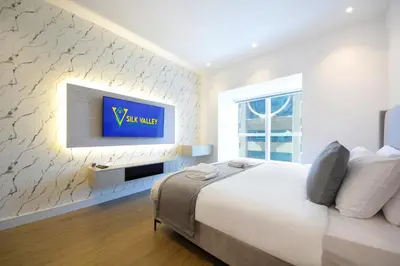 a bedroom with a large bed and a tv on a wall at Silk Valley - Luxury 1BR | High Floor & Balcony | Sea Views in Dubai