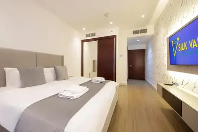 a bedroom with a large bed with a tv on the wall at Silk Valley - Luxury 1BR | High Floor & Balcony | Sea Views in Dubai