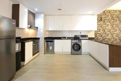 a large kitchen with white cabinets and a dishwasher at Silk Valley - Luxury 1BR | High Floor & Balcony | Sea Views in Dubai