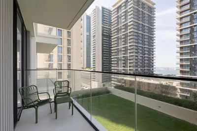 a balcony with two chairs and a view of a city at Modern 1BR in Beach Mansion with Pool and Gym in Dubai