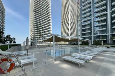 a patio with benches and umbrellas in front of tall buildings at Modern 1BR in Beach Mansion with Pool and Gym in Dubai