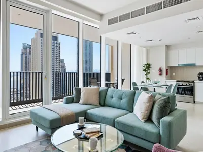 a living room with a blue couch and large windows at Enchanting 2BDR In Creek Harbour 19 in Dubai