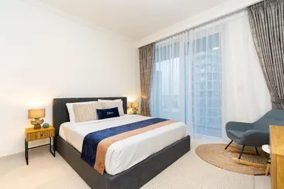 a bedroom with a bed and a chair and a window at CitiHome Elegant 2BR - Private Beach and Marina View in Dubai
